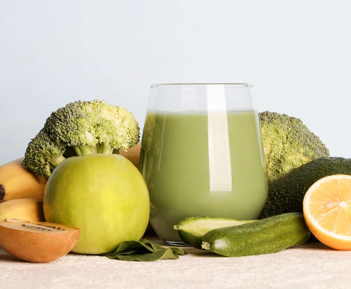 A single glass of NutriFusion green vegetable smoothie positioned between fresh vegetables.