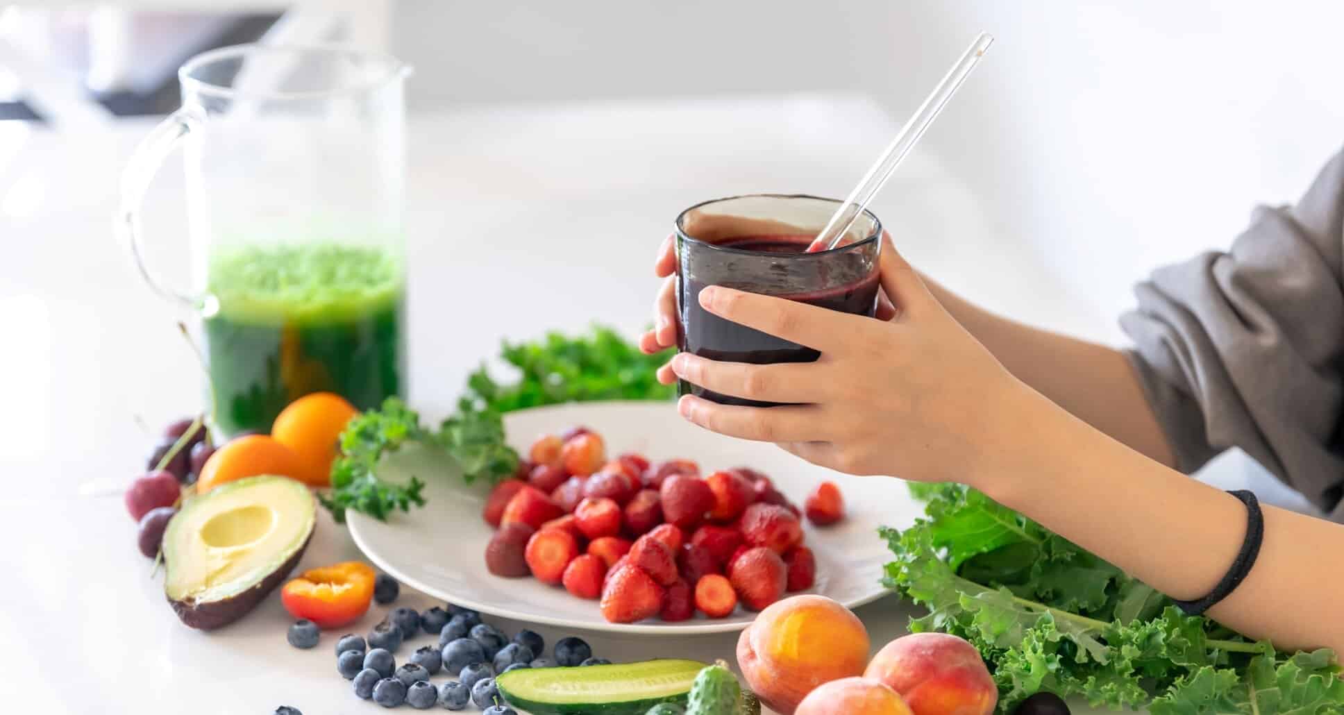 NutriFusion fruit smoothie being held beside fresh berries and greens showcasing plant-based nutrition.