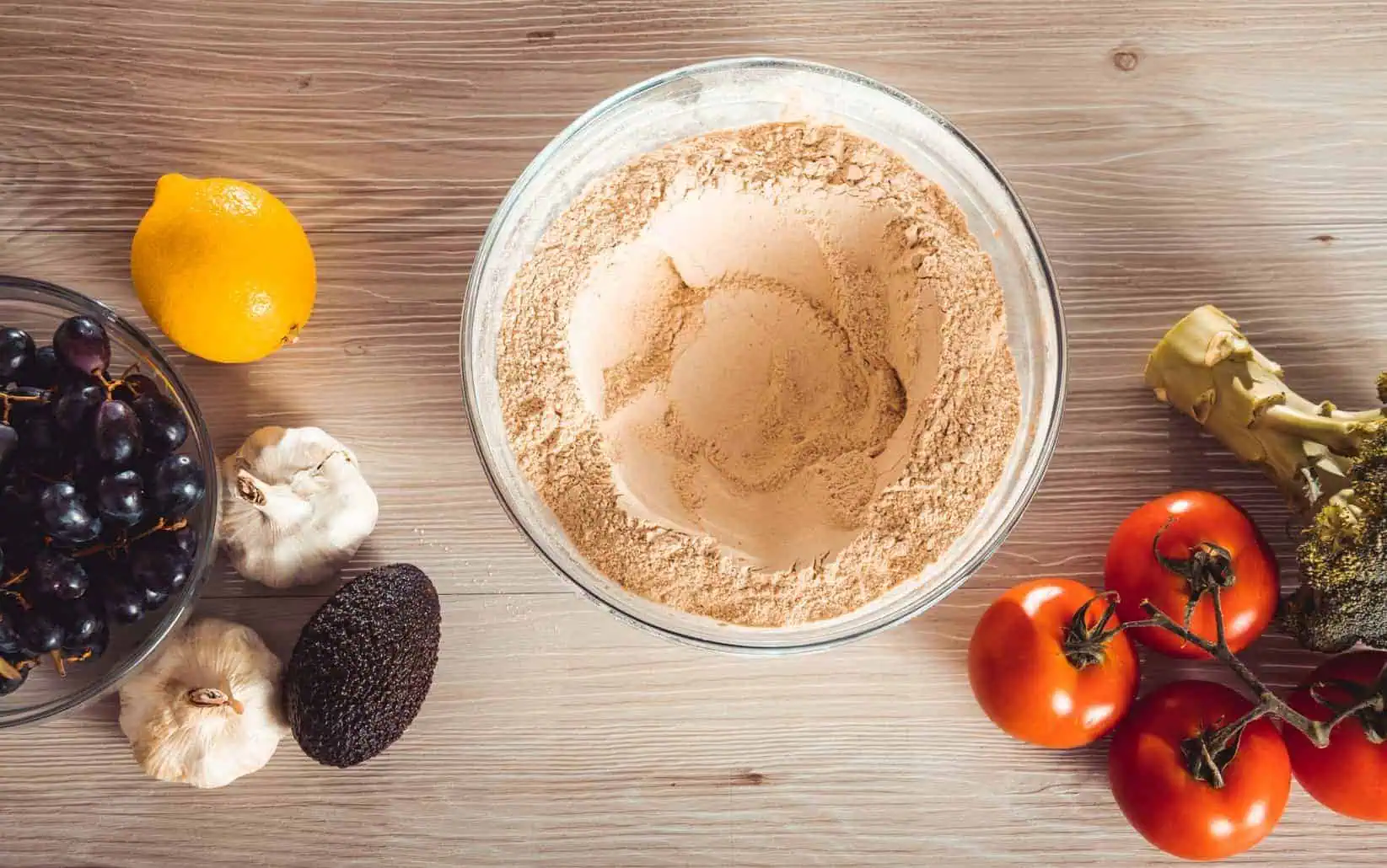 A bowl of NutriFusion's GrandFusion vegetable powder, displayed next to veggies on a wooden surface.