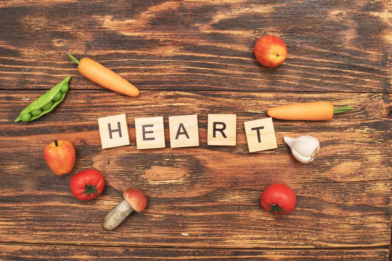 NutriFusion heart-healthy foods with “HEART” letter tiles and fresh produce on a wooden surface.