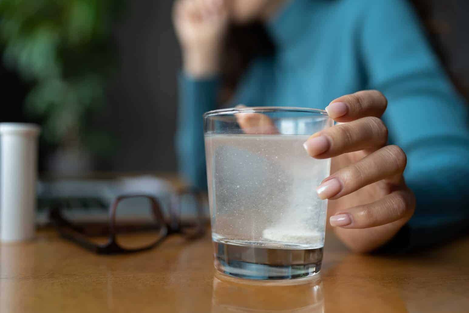 Hand holding a glass of powdered electrolyte supplement into water made with NutriFusion’s powder.