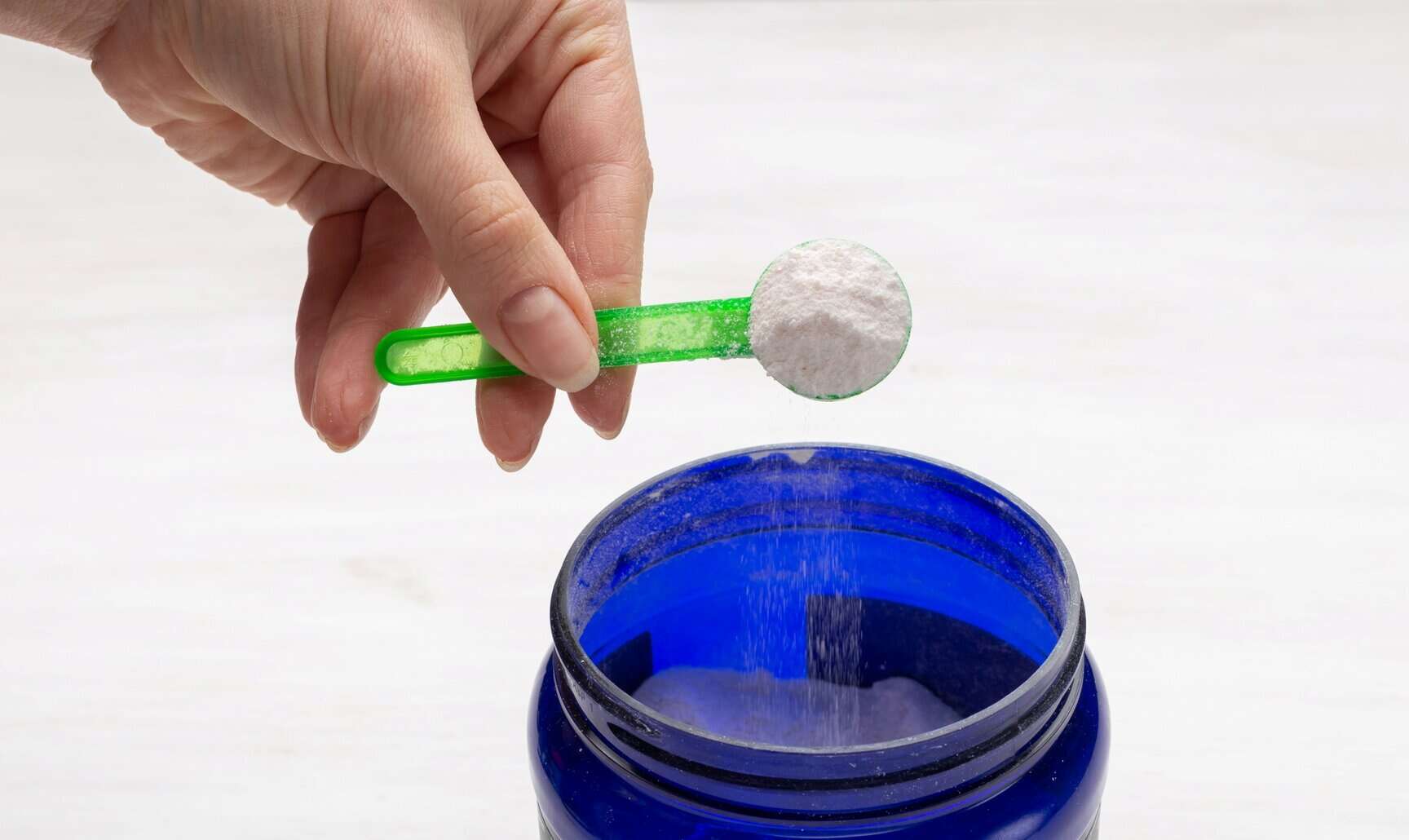 Spoonful of powdered electrolyte supplement infused with NutriFusion blend being added to a container.