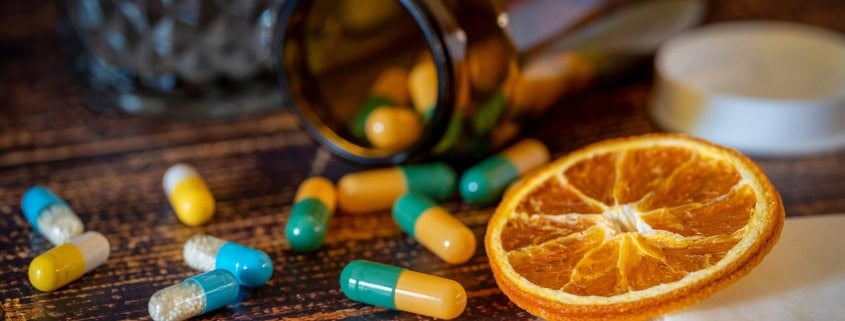 The image shows several medicine pills and an orange peel.