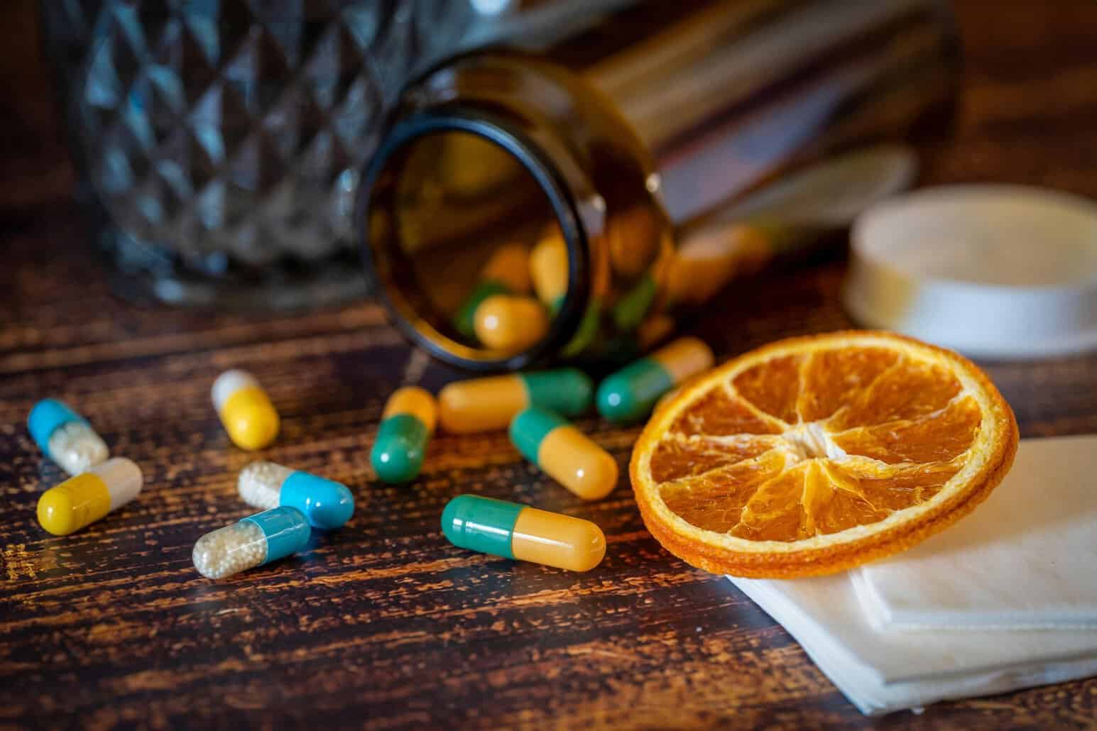 The image shows several medicine pills and an orange peel.