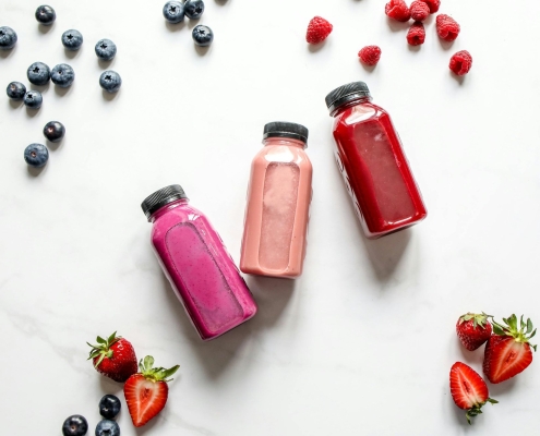 This photo features probiotic drinks laid out on a table with fruits