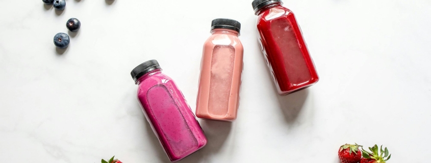 This photo features probiotic drinks laid out on a table with fruits