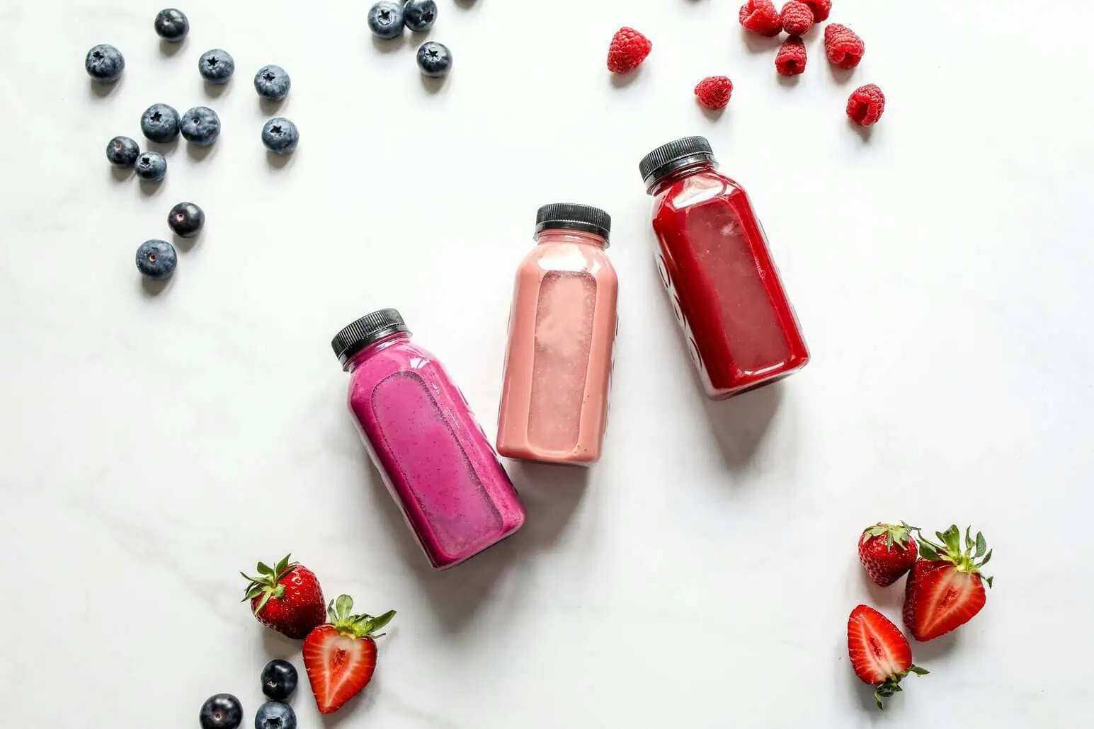 This photo features probiotic drinks laid out on a table with fruits