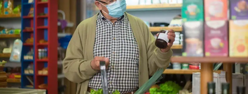 This photo shows a man reading the label of a product at the grocery