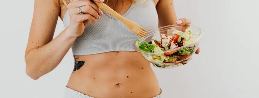 This photo shows a person eating salad with a wooden fork