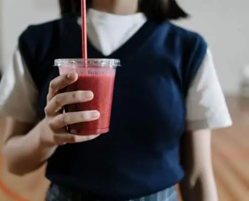 This photo features a woman holding a smoothie