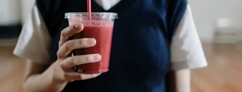 This photo features a woman holding a smoothie
